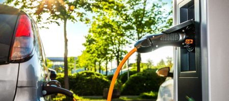 Elektroautos an Ladestation auf Firmengelände im Gegenlicht – Electric Car at Charging Station