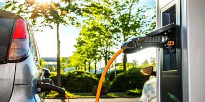 Elektroautos an Ladestation auf Firmengelände im Gegenlicht – Electric Car at Charging Station
